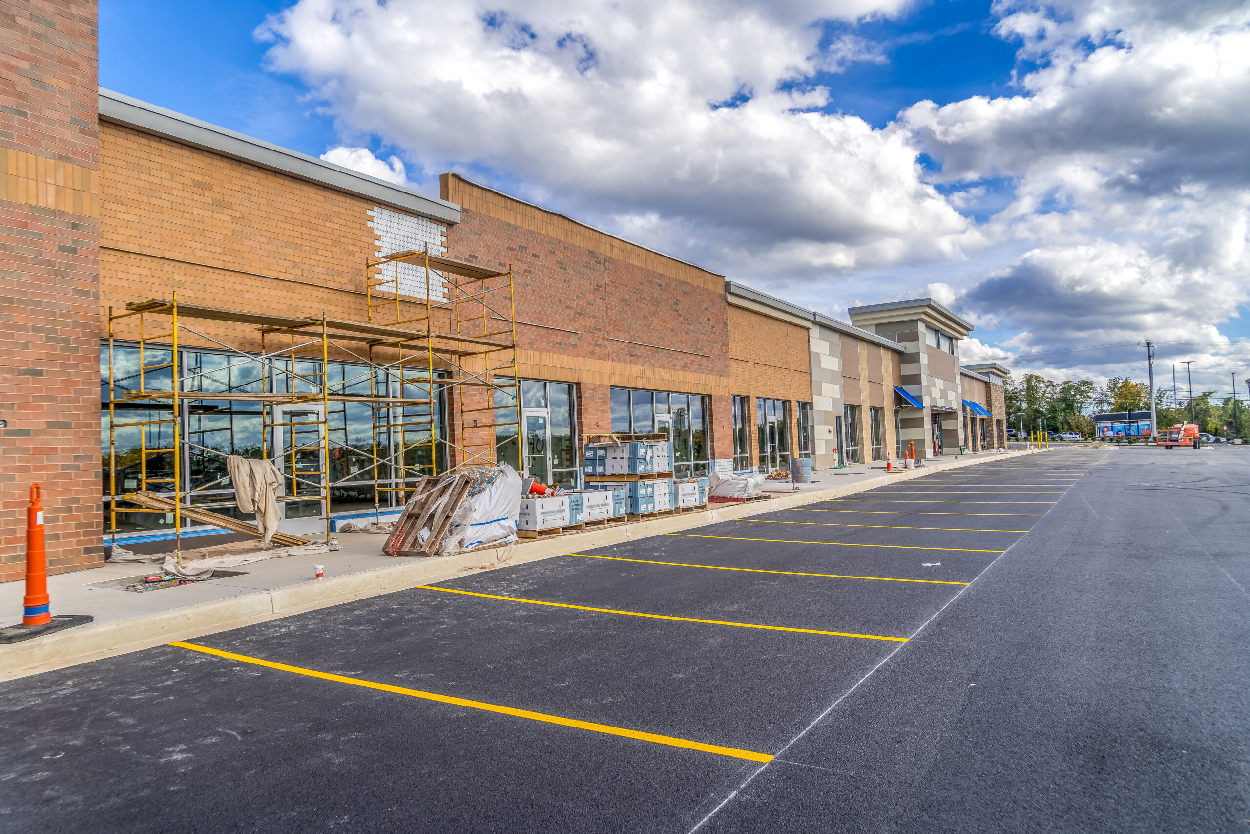 Refurbished strip mall commercial real estate property under construction in Maryland covered with orange, red brick veneer and scaffolding